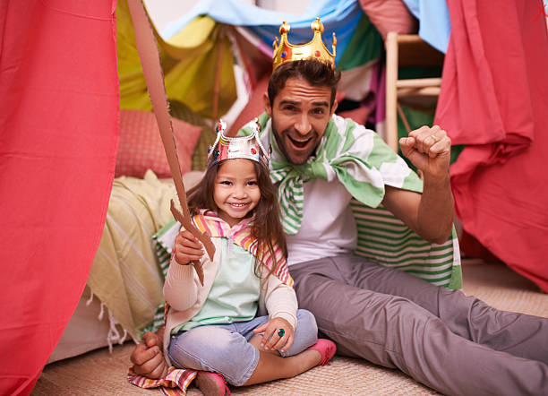 A cute little girl dressed up as a princess while playing at home with her dad