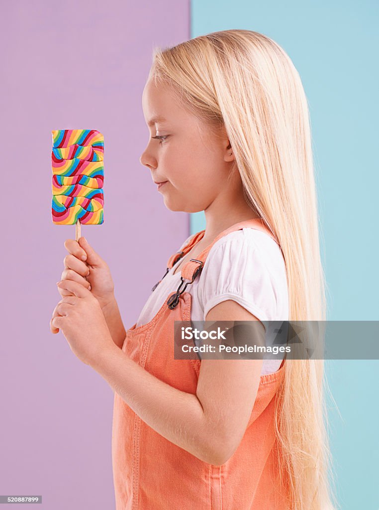 Can't wait to have a bite A cute little girl holding a lollipop while against a colorful background Girls Stock Photo