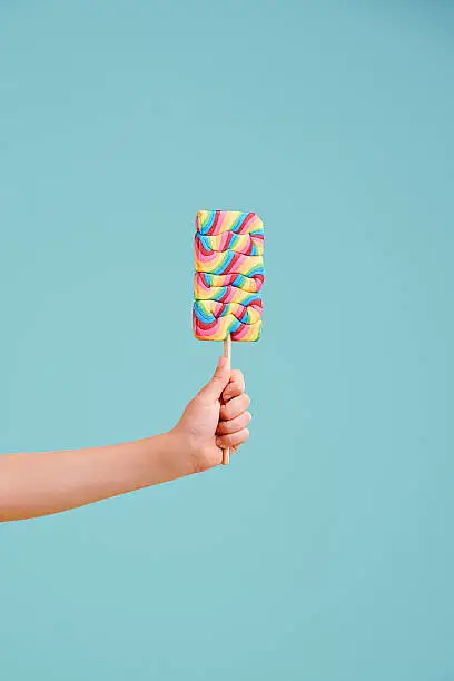A little girl's hand holding a hard candy lollipop