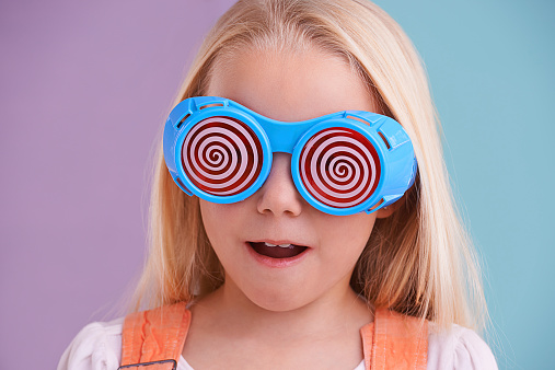 A cute little girl wearing funny sunglasses against a colorful background