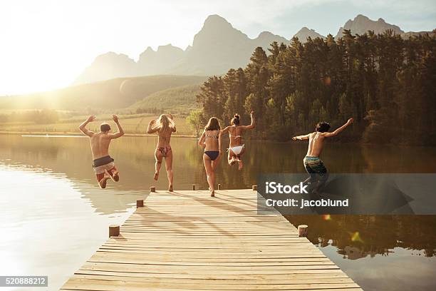 Group Of Young People Jumping Into The Water Stock Photo - Download Image Now - Lake, Swimming, Jumping
