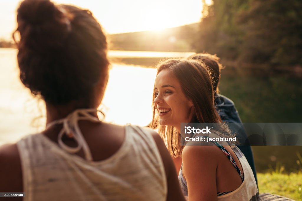 Heureuse Jeune femme assise sur un lac avec ses amis - Photo de Amitié libre de droits