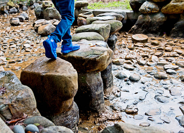 Little boy crossing stepping stones.
