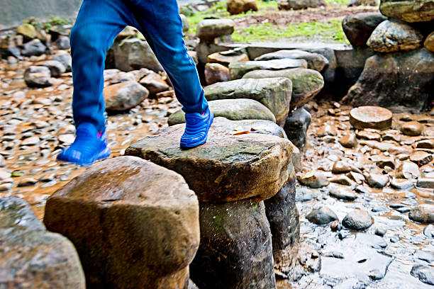 istock Boy legs crossing stepping stones 520888940