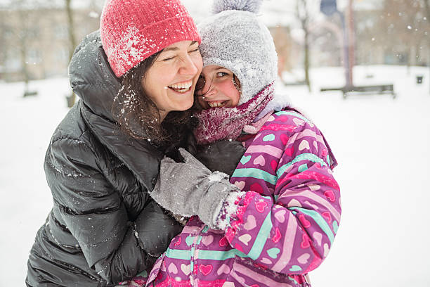 Mother and daughter having fun playing in fresh fallen snow.