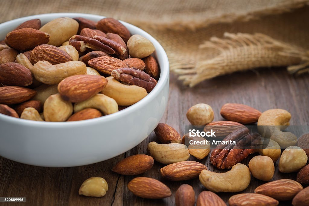 Mixed nuts on wooden table and bowl Nut - Food Stock Photo
