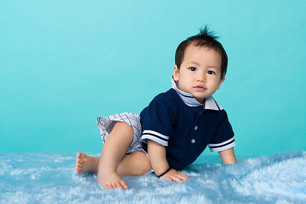 Adorable Asian Chinese baby boy sitting on blue background stock photo