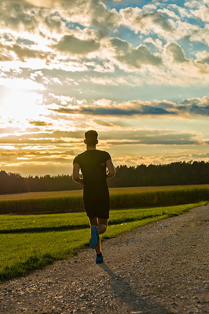 istock Back view of man running on the road at sunset 520890480