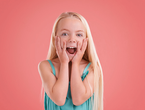 Studio shot of a cute little girl posing against a red background