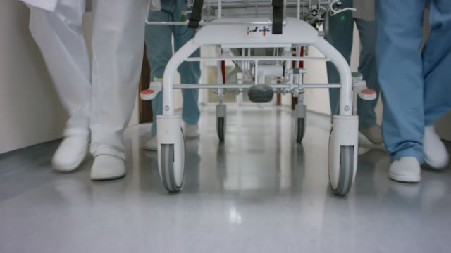 DS Legs of the medical team pushing a gurney down the hospital hallway