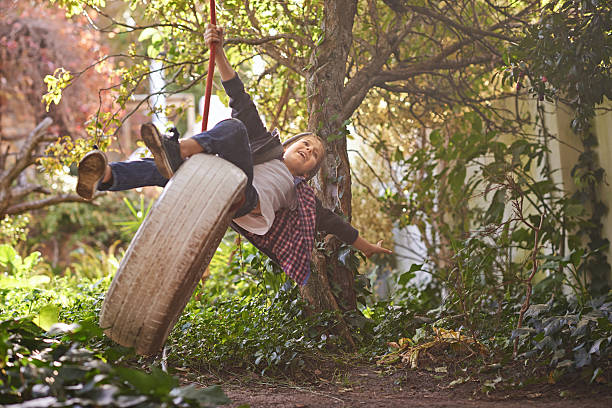 Busy making childhood memories A cute preteen boy swinging on a tyre swing in the garden tire swing stock pictures, royalty-free photos & images