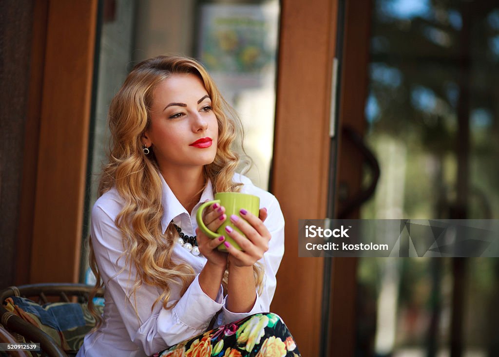 Pensive woman sitting with coffee cup outdoors Pensive woman sitting with coffee cup and has a rest in spring cafe outdoors and dreaming looking far away Adult Stock Photo