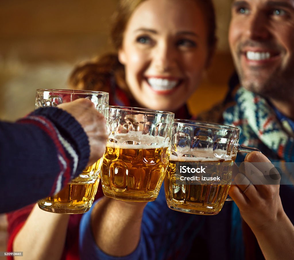 Friends toasting with beer Group of friends wearing warm clothes toasting with beer. Focus on beer glasses. Apres-Ski Stock Photo