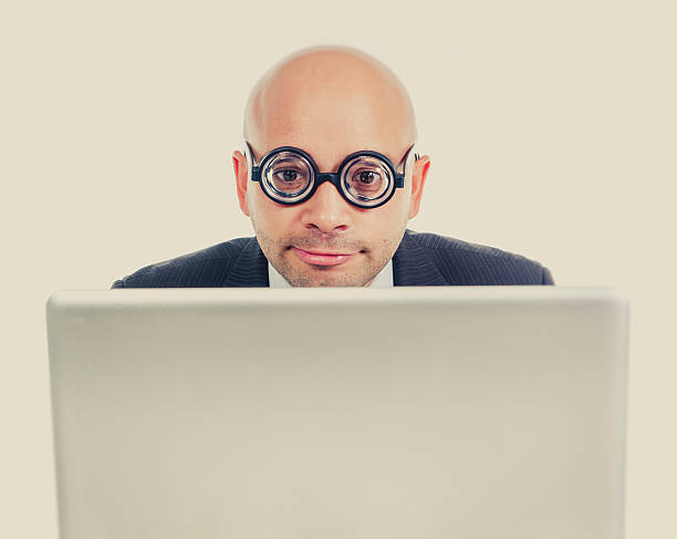 istock geek and freak bald head businessman with computer laptop 520916263