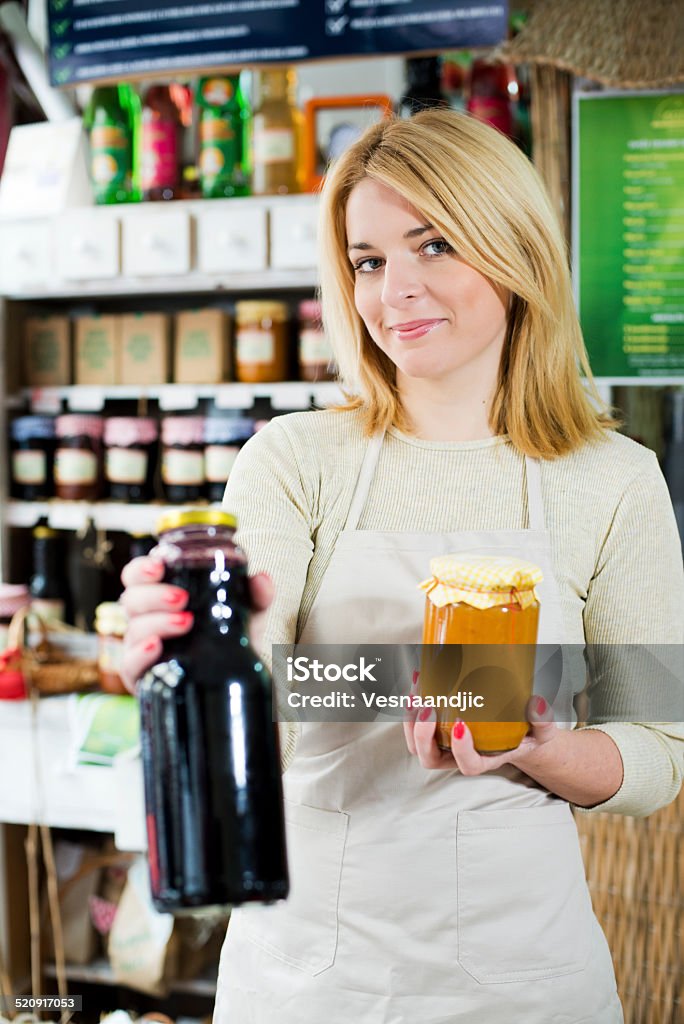 Young woman holding homemade jam and juice at shop Mature Women Stock Photo