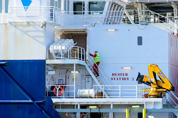Person climbing stairs at ship Karlskrona, Sweden - April 7, 2016: Male person climb some stairs at muster station 2 aboard the industrial cable transport ship Topaz Installer moored beside the ABB factory. muster station stock pictures, royalty-free photos & images