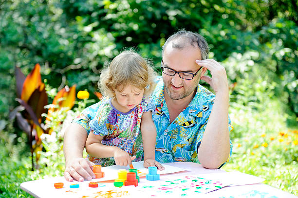 istock Father and daughter sitting at a table outdoors, draws 8. 520941522