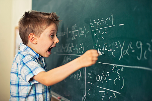 Funny little boy writing math formula. Looks like he's discovered something amazing and very important.
