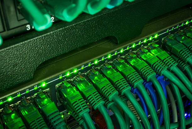 istock Close up of green network cables connected to switch glowing 520945372