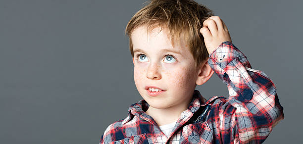 istock sweet red hair little boy scratching head for imagination 520947168