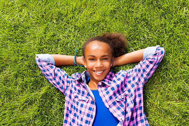 istock Smiling beautiful African girl laying on grass 520947179