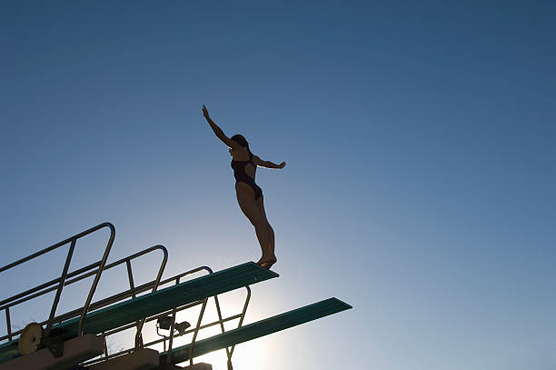 kobiet pływak stać na platforma do skoków do wody o zachodzie słońca - diving board zdjęcia i obrazy z banku zdjęć