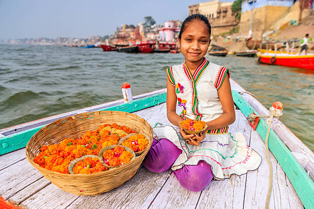 petite fille à la vente des fleurs, des bougies en bateau du gange, varanasi - india ganges river indian culture varanasi photos et images de collection