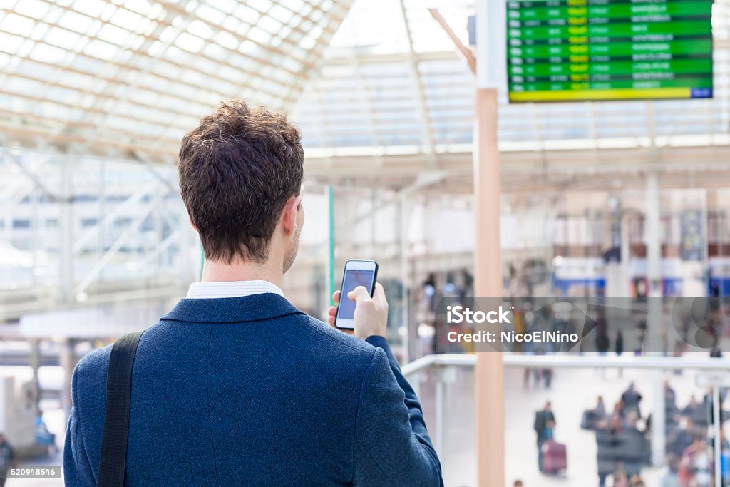 Voyageur envoi de SMS sur smartphone dans la gare ferroviaire - Photo de Train libre de droits