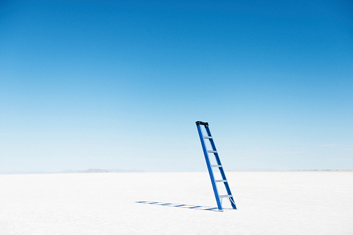 Blue ladder balanced in the middle of the desert. Stairway to heaven