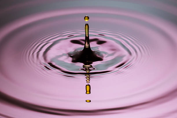 istock Yellow drop pillar close up ripples pink blue gray surface 520964493