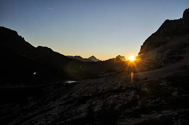 Stunning sunrise photo shot while hiking up Mount Marmolata (Marmolada). Marmolata is the highest mountain in the Dolomites (3343m). On the left you can see the reservoir lake Lago di Fedaia, the two mountains in the background are Monte Antelao and Monte Pelmo.