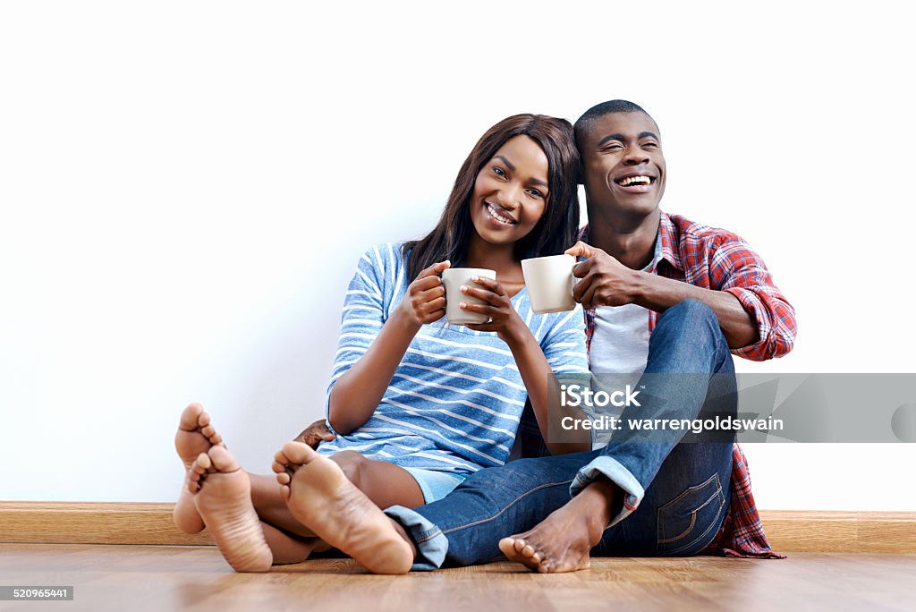 new apartment couple Young african couple sitting on floor of new home with coffee and being happy with life success of property investment Adult Stock Photo