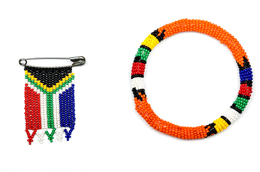 Colorful Zulu beads threaded into an armband and a south african flag on white