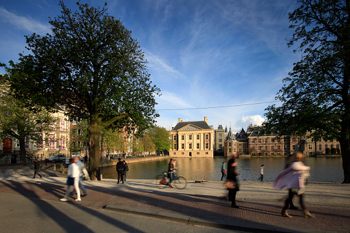 The Hague, Netherlands - April 13, 2016: people along the Hofvijver, with the exterior of the famous Mauritshuis and Dutch parliament buildings in the background, in The Hague