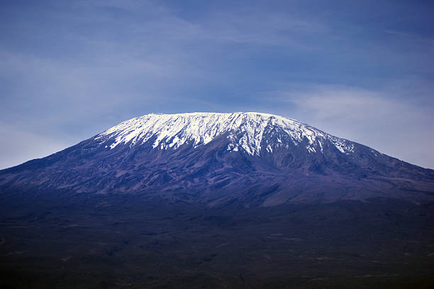 A lonely male hiker is taking pictures from a black bird nearby at the edge of the crater of Mount Meru (4.562 mt,, 14.967 ft.) in Tanzania. The area is famous for hiking and to get acclimated for further hikes on Mount Kilimanjaro which is visible in the distance.\nCanon EOS 760D, 1/200, f/25, 29 mm.