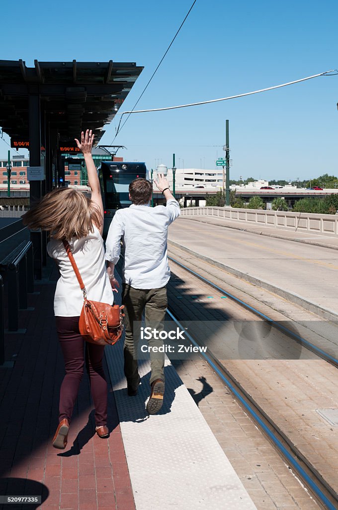 Young Couple Missing Train An attractive, young, married, heterosexual couple run after a train they have just missed in Houston, Texas on a beautiful autumn afternoon.  Running away from the camera position with their arms waving in the air, frantic and frustrated. Adult Stock Photo