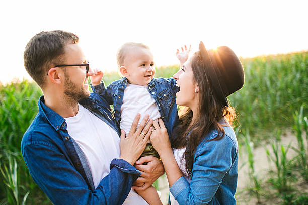 Young hipster father mother holding cute baby in corn field stock photo