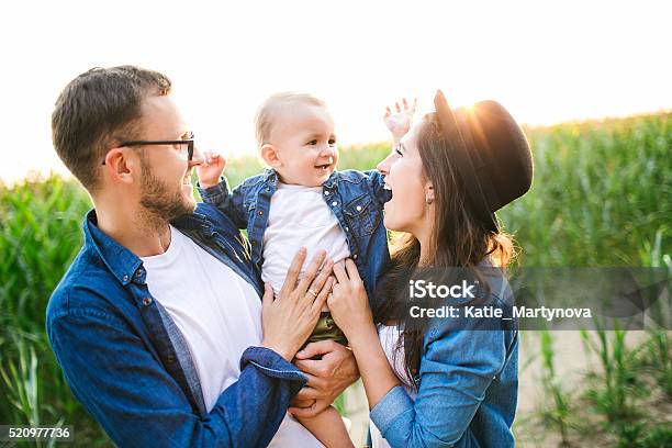 Foto de Jovem Bonito Hipster Pai Mãe Segurando O Bebê No Campo De Milho e mais fotos de stock de Família