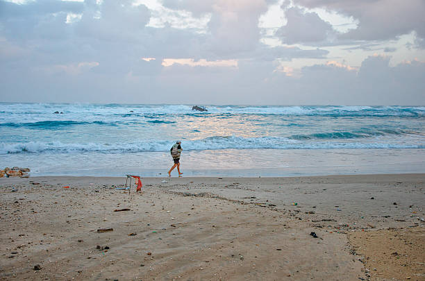 uomo anziano camminare rapidamente in inverno stormy beach - wave sea storm water foto e immagini stock