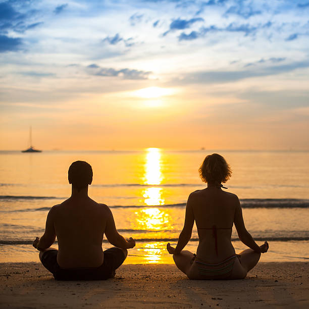 istock Young couple practicing yoga on sea beach during amazing sunset. 520980927