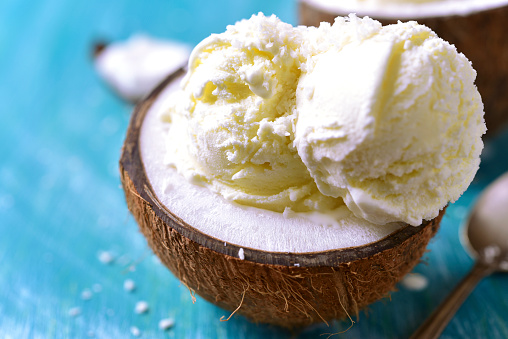 Ice cream in a coconut on a blue wooden table.
