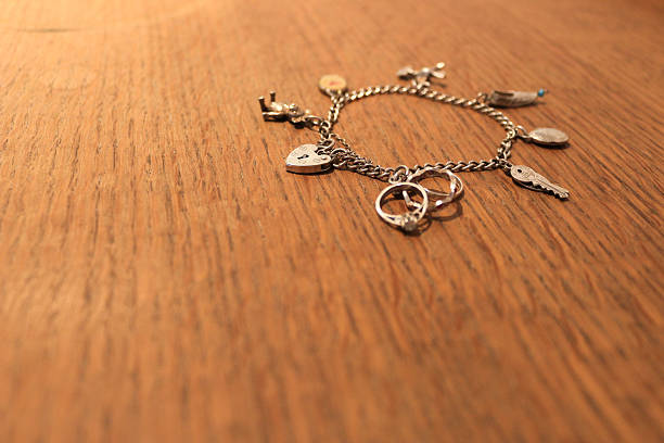 istock Silver charm bracelet on a scratched wood surface 521002483