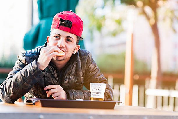 istock Young man eating hamburger at sidewalk cafe 521006191