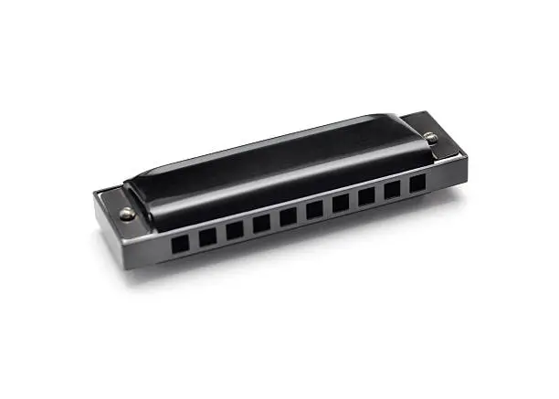 Closeup of a mass produced harmonica on a white background with shadows.  