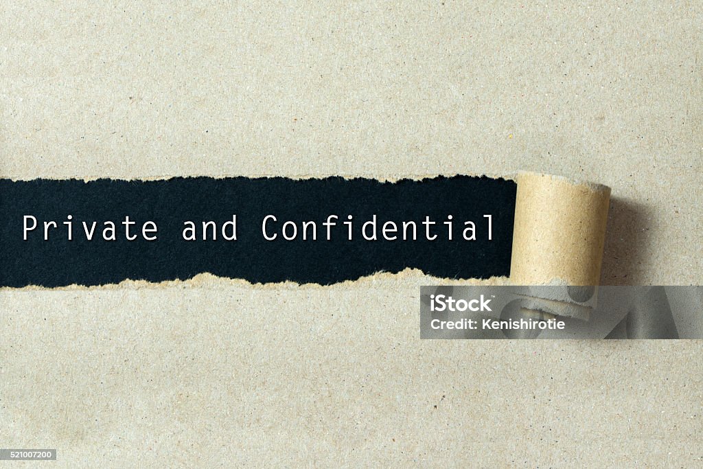 Private and confidential Private and confidential written on torn paper black background Privacy Stock Photo
