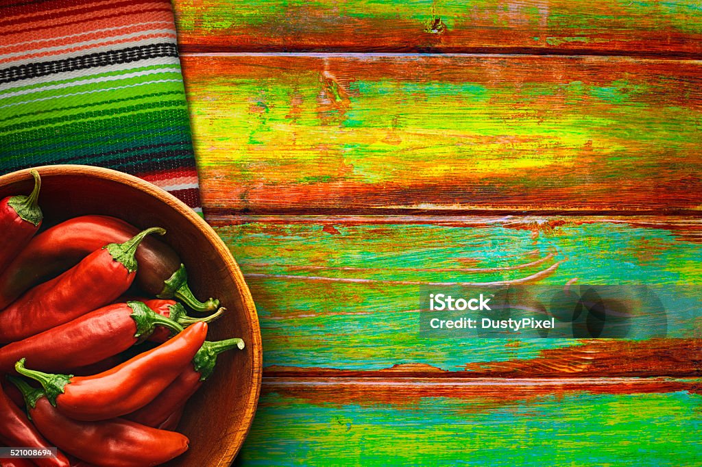 Bowl of Red Chili Peppers on Vibrant Background Red chili peppers fill a wooden bowl on vibrantly colored wood background Mexican Food Stock Photo