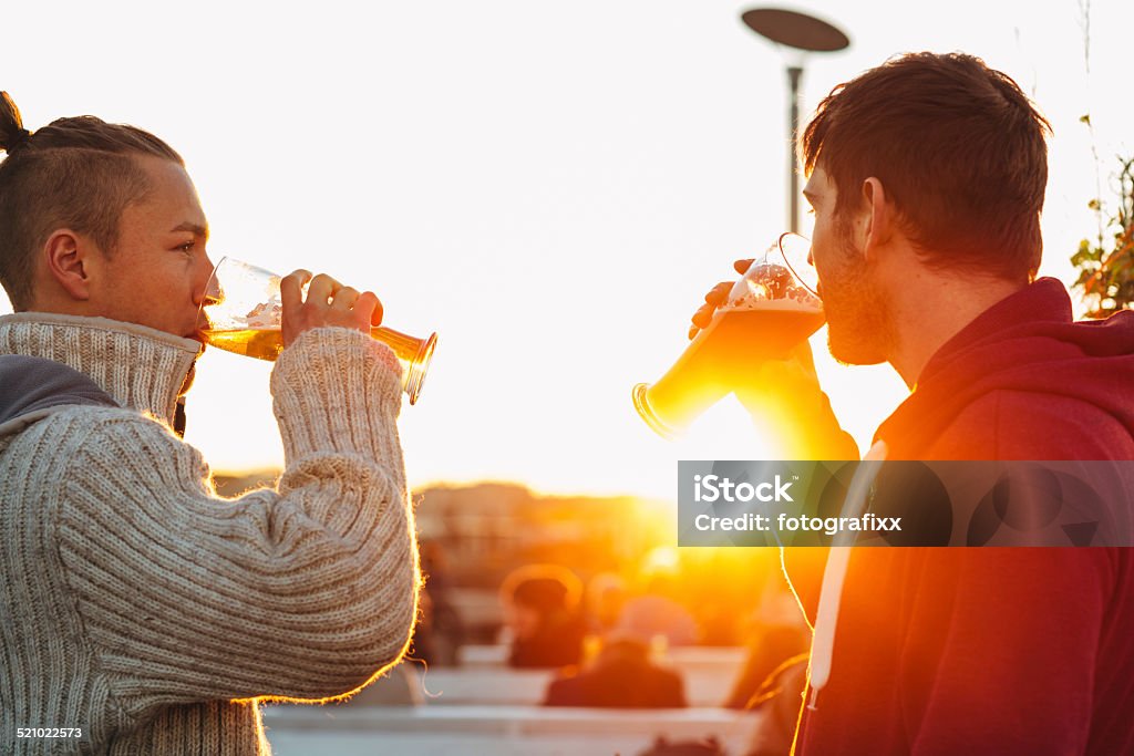 handsome young men drinking beer in front of backlit handsome young men drinking beer Autumn Stock Photo