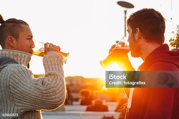Handsome Young Men Drinking Beer In Front Of Backlit Stock Photo - Download Image Now