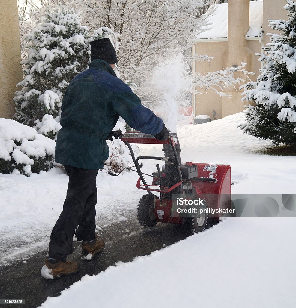 Man Using Snow Blower A man uses a snow blower to remove snow from a driveway during a winter storm Snowblower Stock Photo