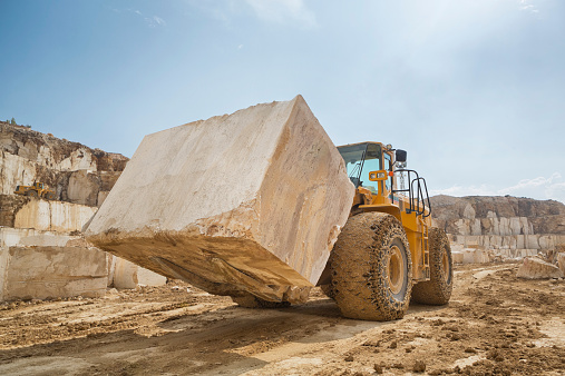 A very big marble rock block carried by a forklift in a quarry.
